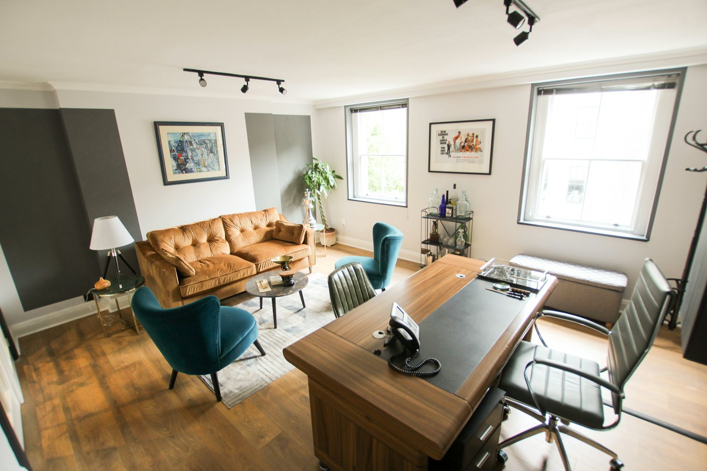 Contemporary office space with sofa, armchairs, and desk.